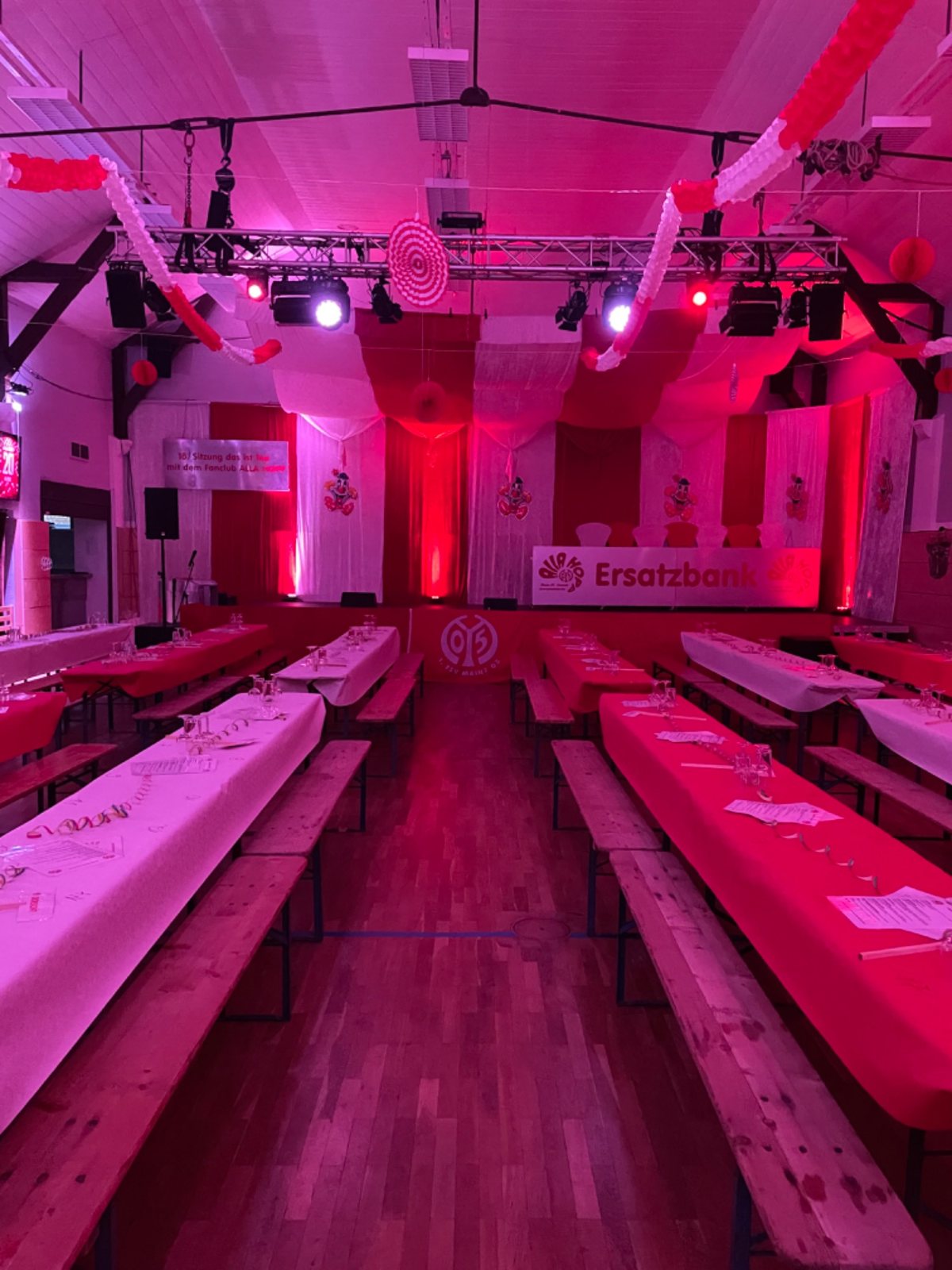 Festhalle in rotem Ambientelicht mit Bierzeltgarnituren